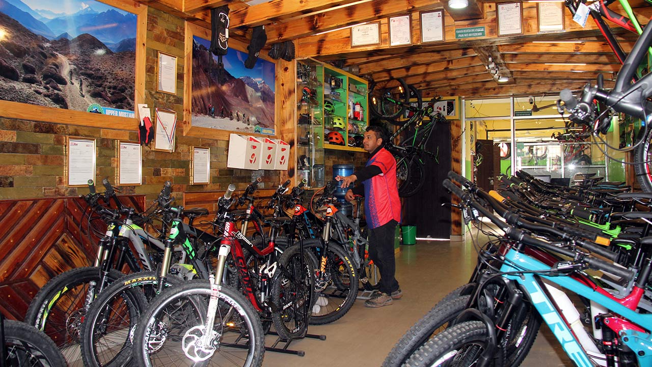 A man in red and blue t-shirt is checking the mountain bikes at the mountain bike shop at Pokhara Mountain Bike Adventure.