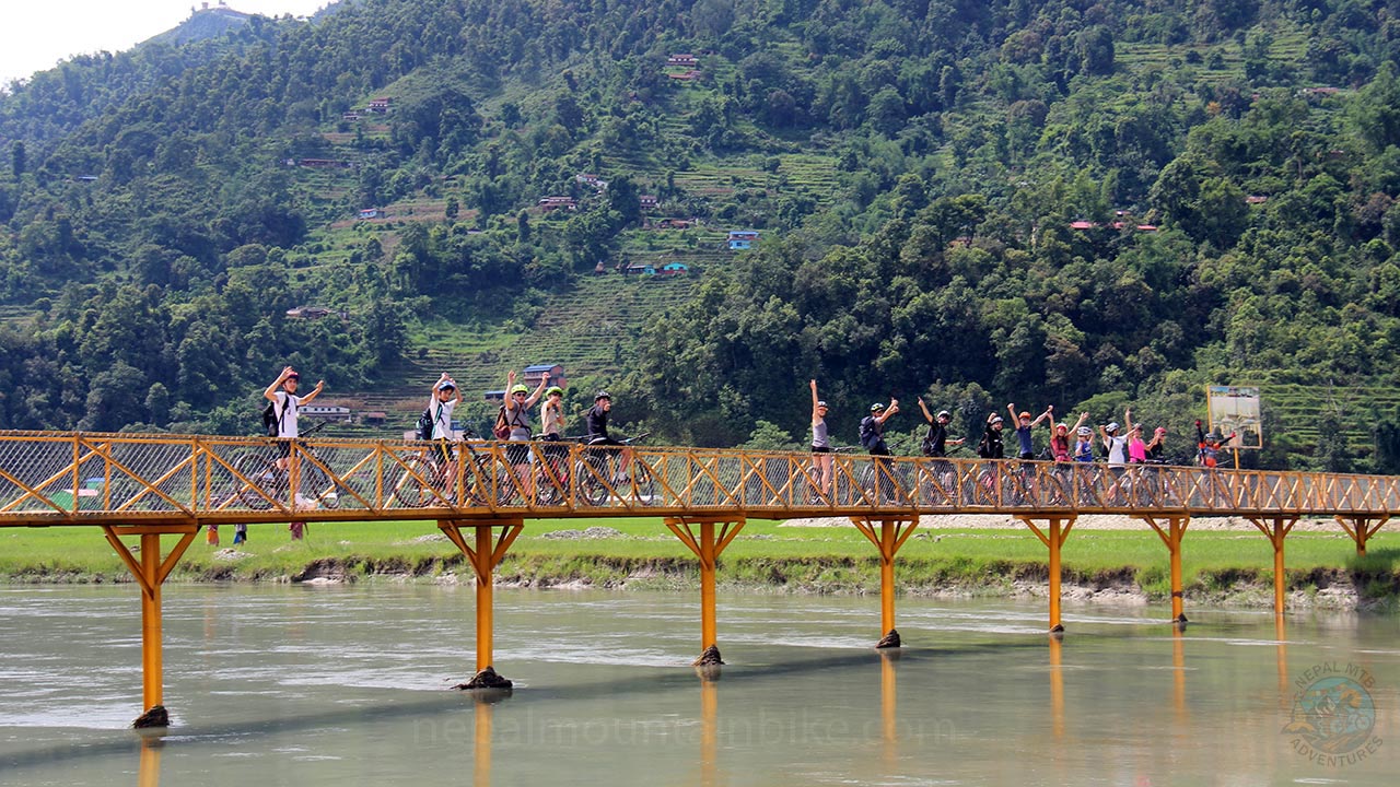 A group of college students are cheering with their hands raised up during their mountain bike tour in Pokhara.