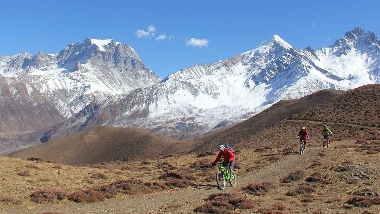 Three mountain bikers are rolling down the Lupra single track in Lower Mustang during Nepal mountain bike tour.