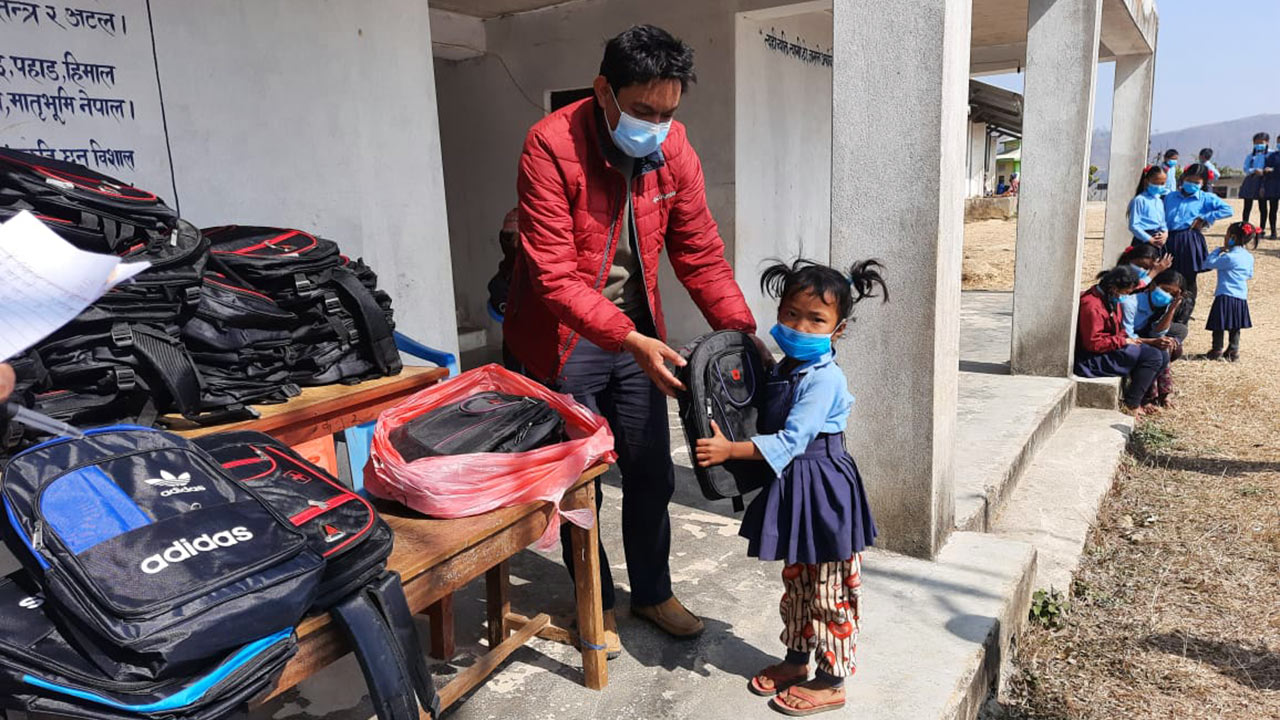 A girl from a disadvantaged community is receiving a bag.